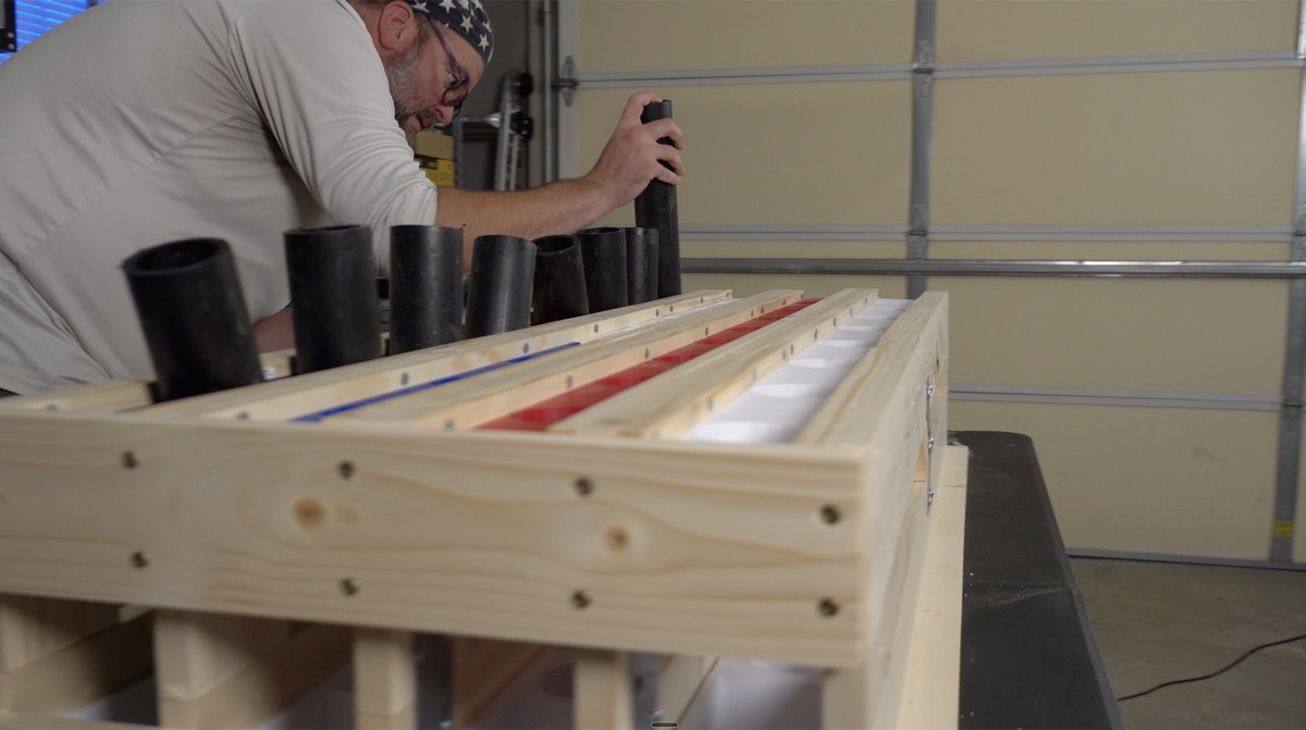 Loading black HDPE mortar tubes into the assembled wooden rack